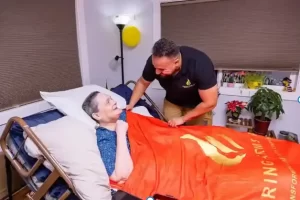 senior lying on bed after hospital discharge being taken care by friendly nurse and caregiver at Caring Arms of Bonney lake