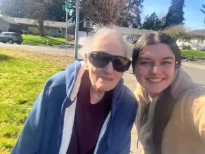 caregiver from caring arms adult family homes of Bonney lake giving company to a senior resident going out for a walk in residential neighbourhood